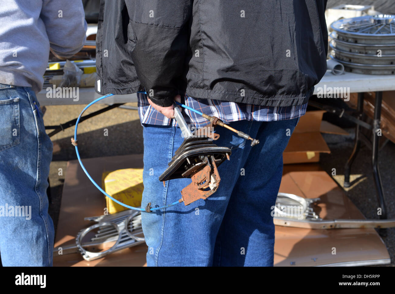 Buyer picks up a gear shift among car parts for sale at a swap meet at