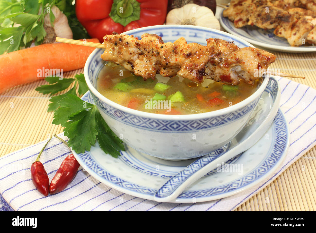 a bowl of chicken consomme and a chicken skewer Stock Photo