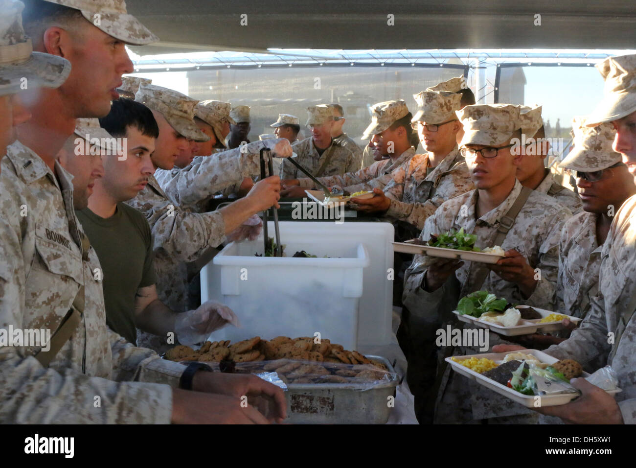 Marines with 1st Battalion, 7th Marine Regiment, serve food to one another during a warriors' meal here, Oct. 19, 2013. The battalion was rewarded with the meal for completing Weapons and Tactics Instructor course. WTI is held biannually and provides an o Stock Photo