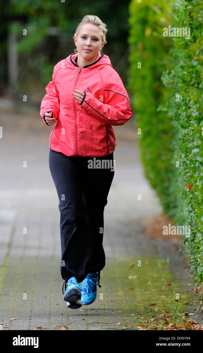 Young woman jogging and wearing a windbreaker jacket in autumn Stock Photo