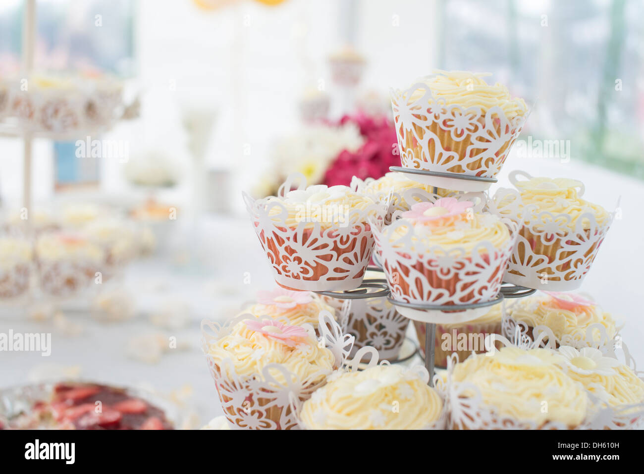 Fancy wrapped fairy cakes on cake stand with decorated tablecloth Stock Photo