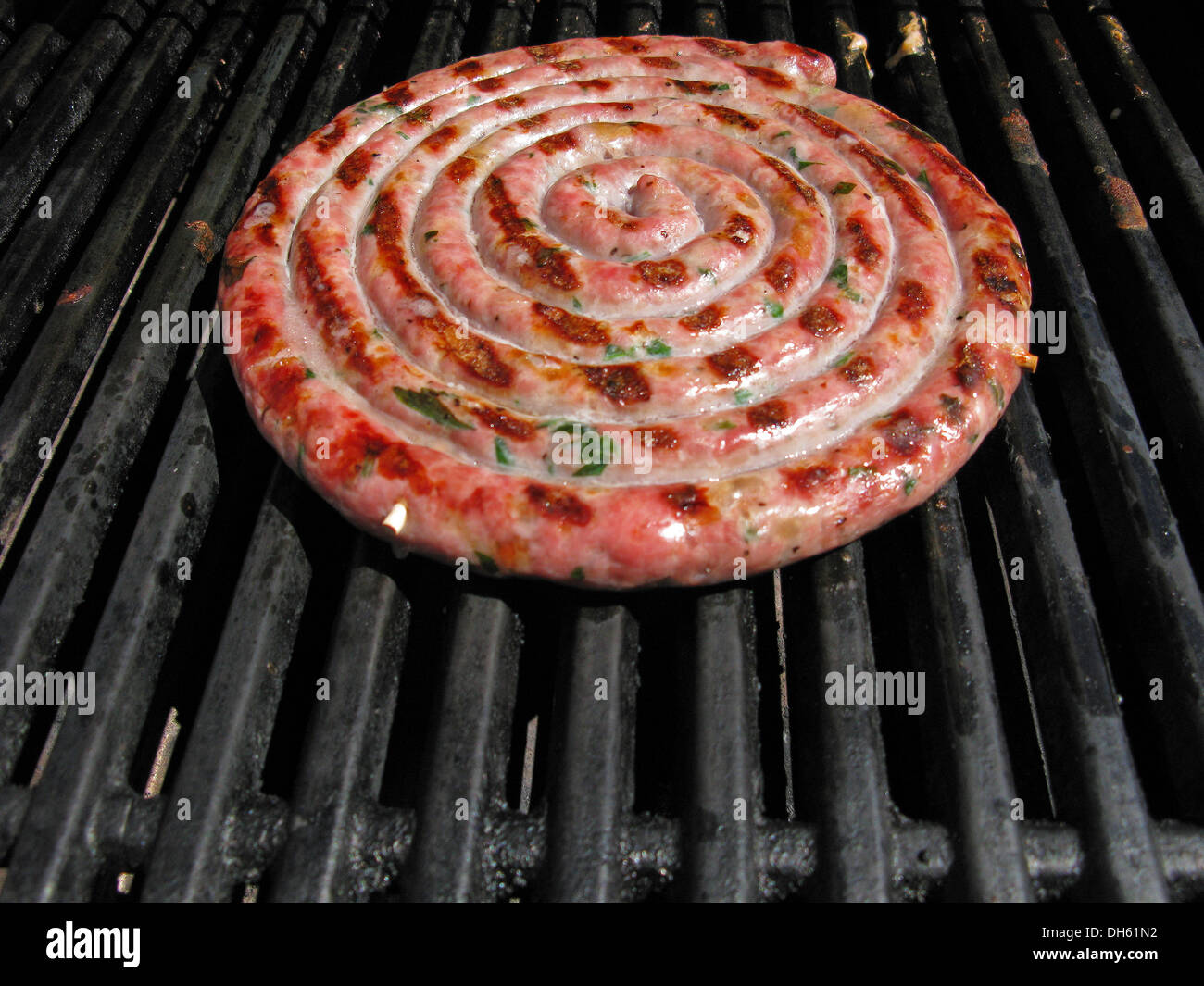 A round ring of meet sausages on a cooking grill. Stock Photo