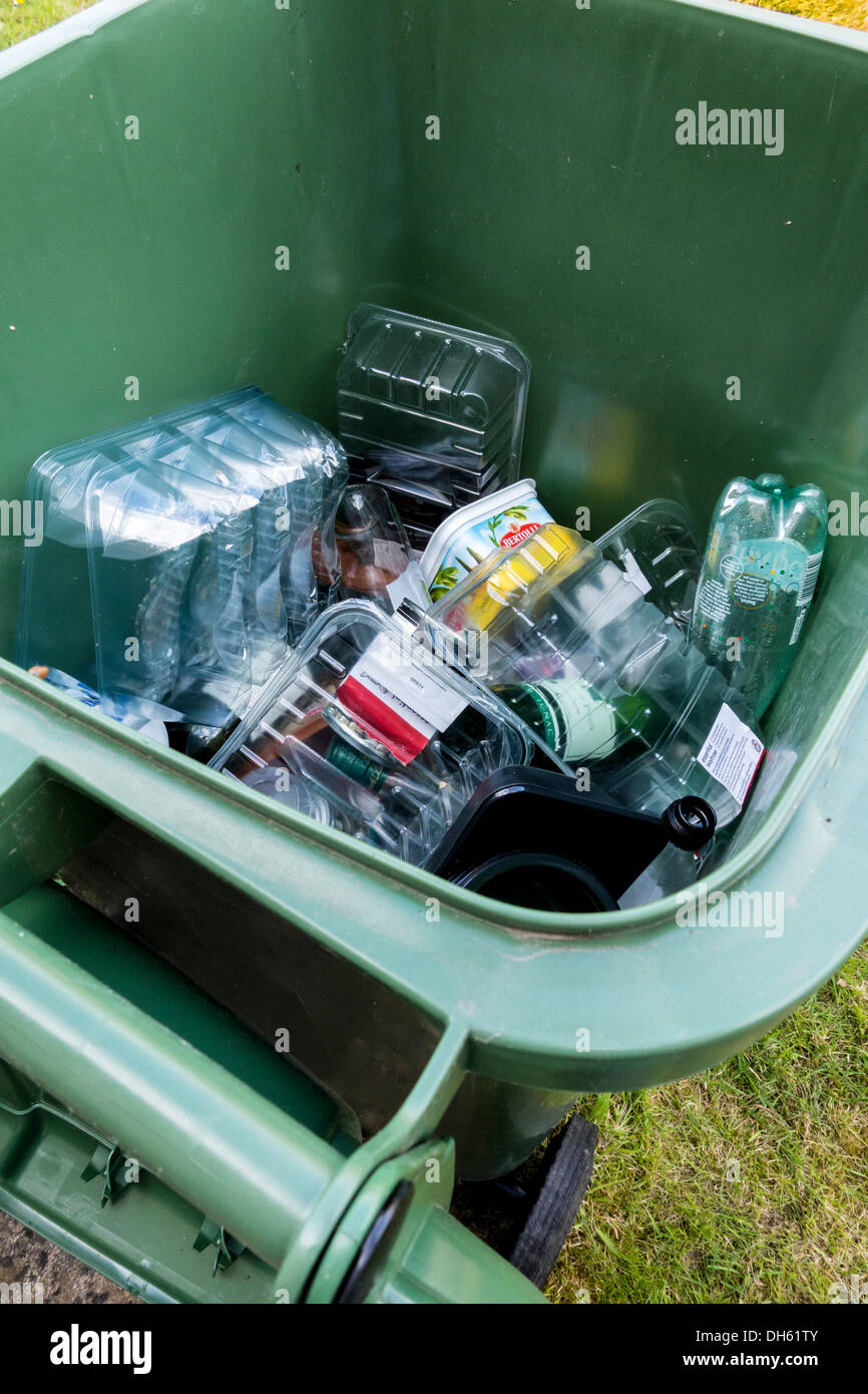 Green wheely bin full of plastic food containers for recycling collection, UK Stock Photo