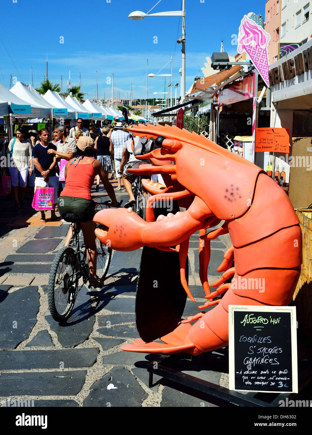 Large advertising langoustine appears to be pinching bottom of passing cyclist, Cap D'Agde, France Stock Photo