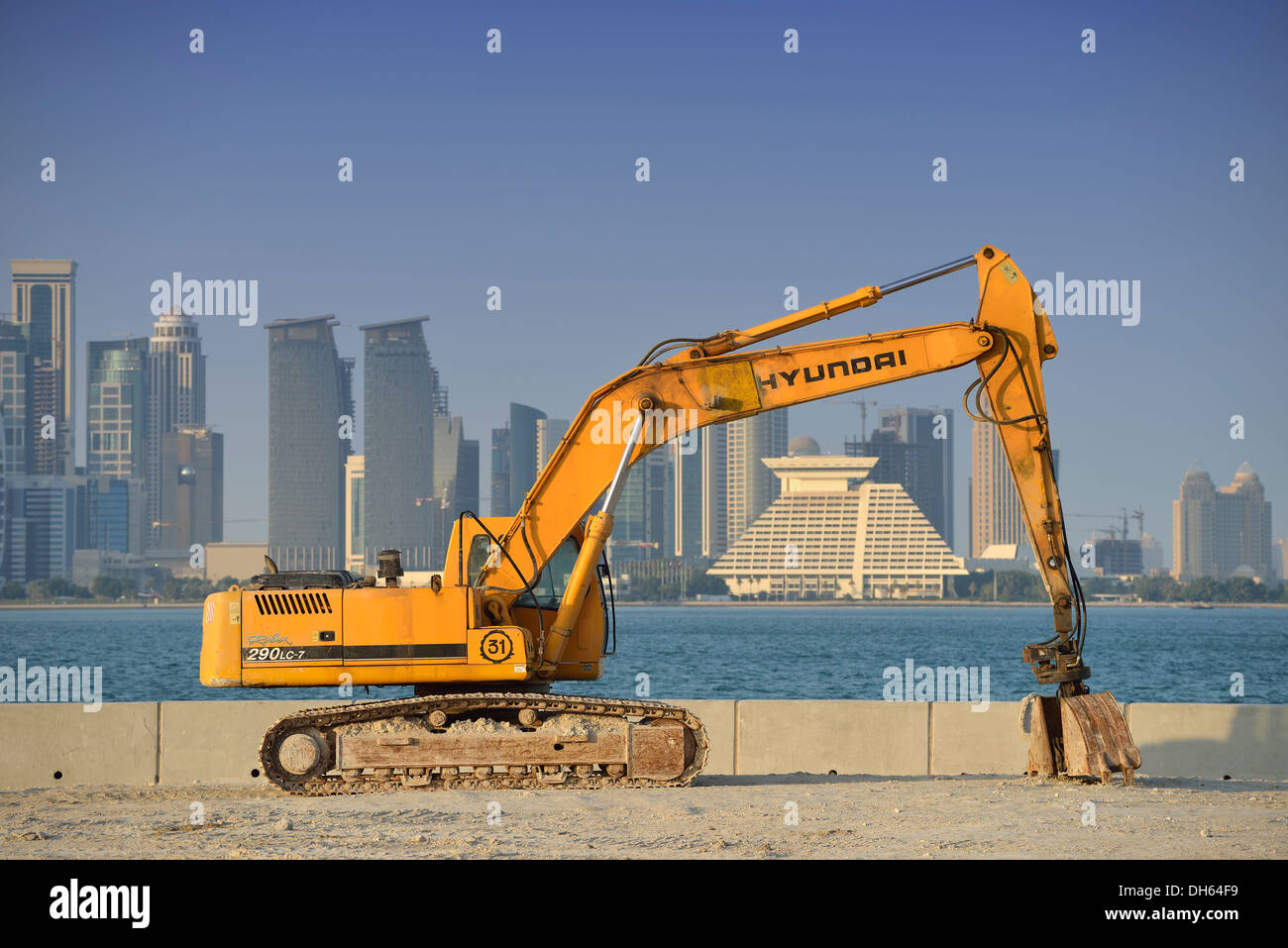 Building boom in Doha, Hyundai excavator in front of the skyline of Doha with Doha Sheraton Hotel, Four Seasons Hotel Stock Photo