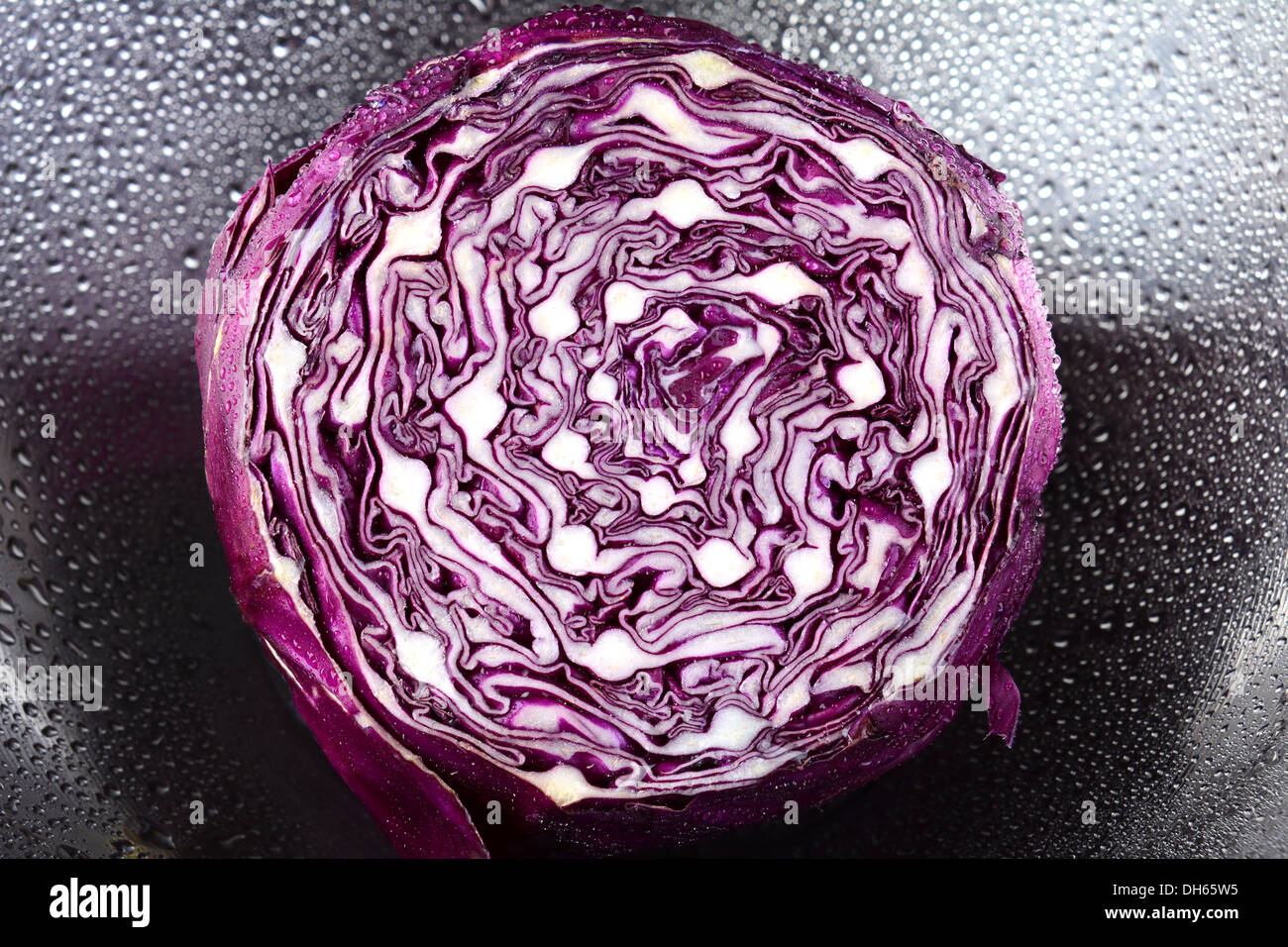 Closeup of a head of red cabbage in a stainless steel bowl with water droplets. Stock Photo