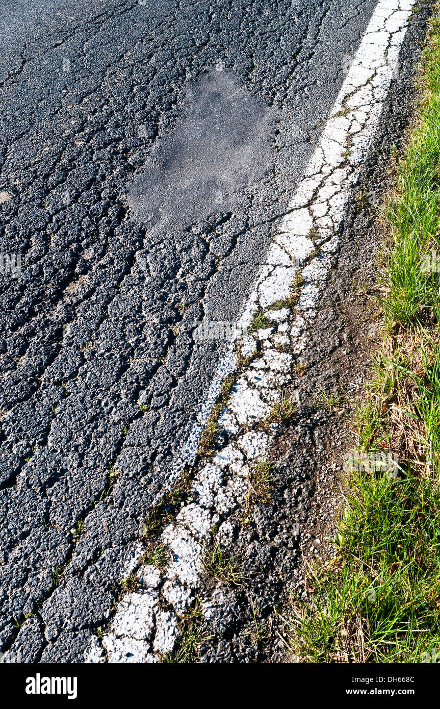 Cracked road surface and roadside verge - France. Stock Photo