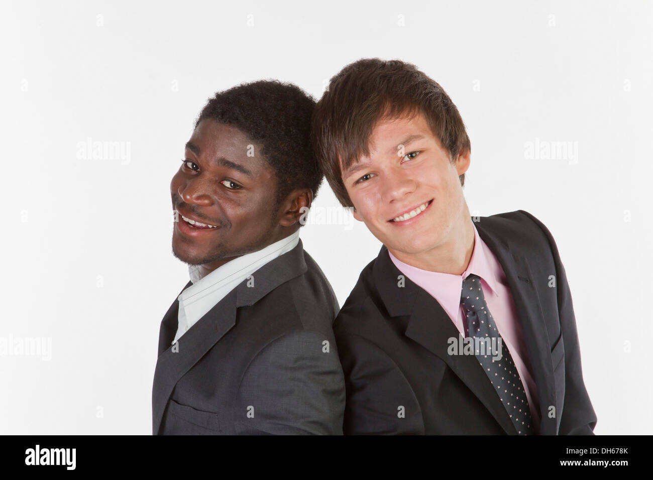 Two young businessmen standing back to back and smiling Stock Photo - Alamy