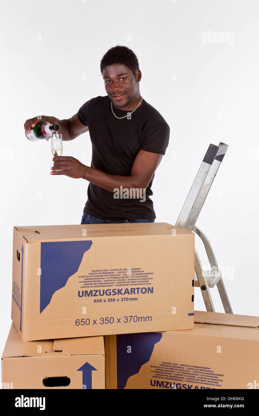 Young black man with moving boxes and a bottle of champagne Stock Photo