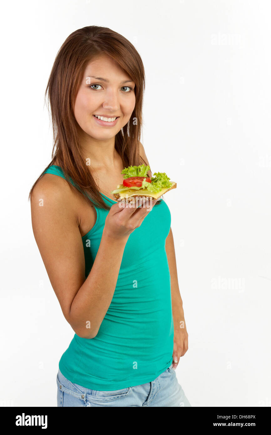 Young woman with grain bread topped with cheese and tomato, smiling Stock Photo