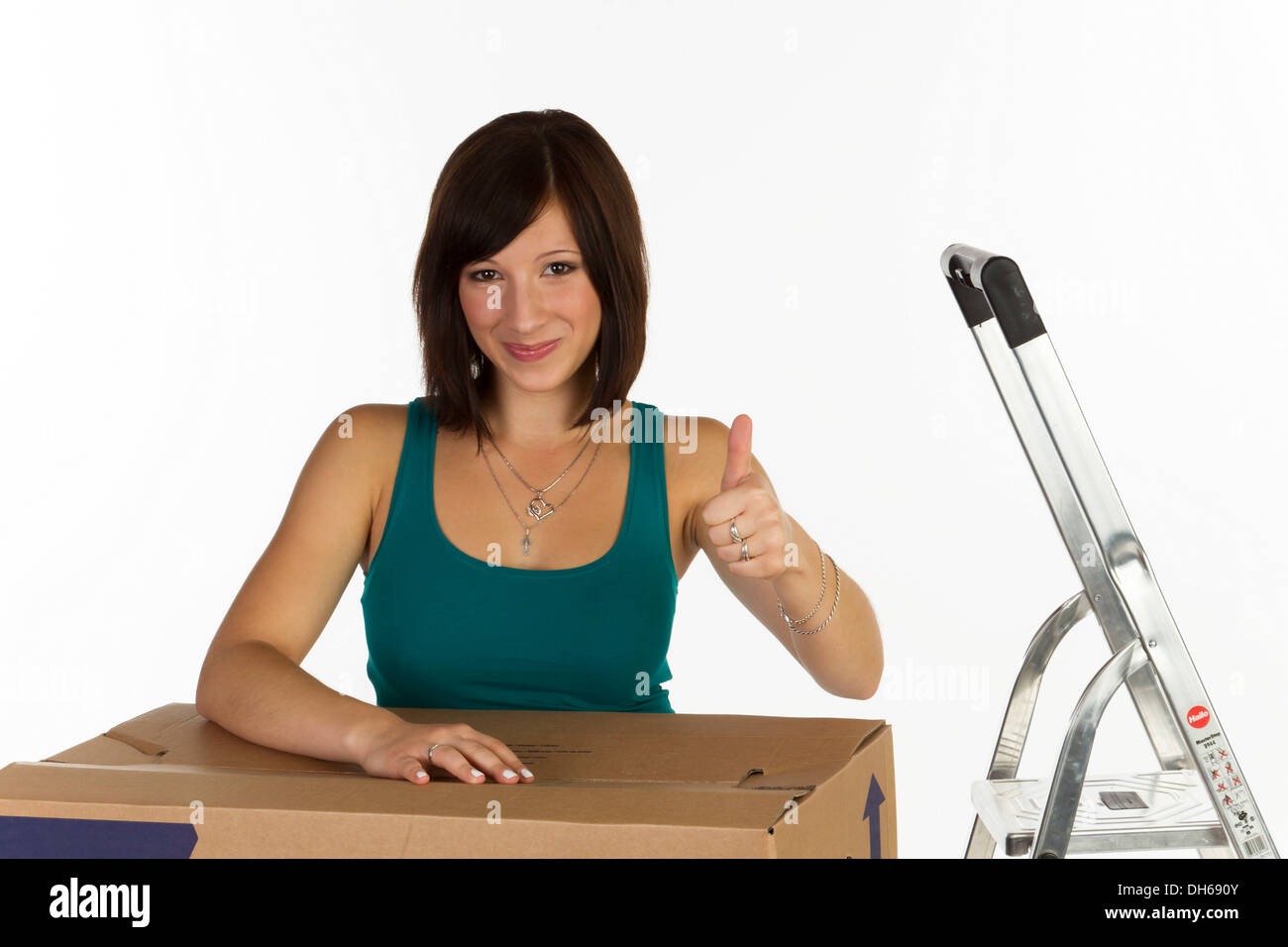 Young woman with a moving box, making a thumbs-up gesture Stock Photo