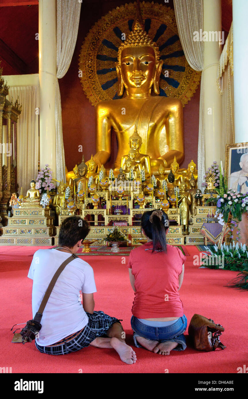 Couple kneeling in front of a Buddha statue, Chiang Mai, Thailand Stock