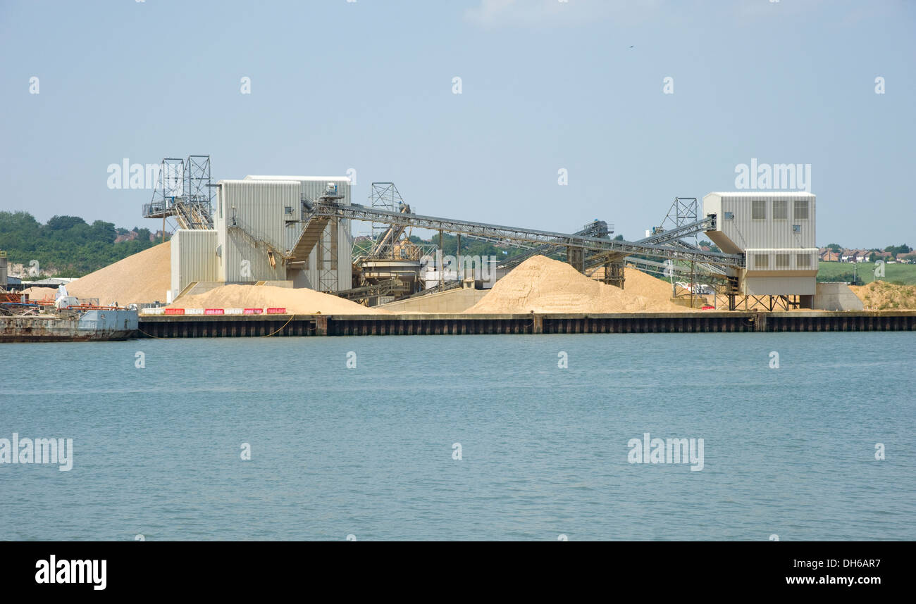 An industrial gravel plant. Storage of sand and gravel, with conveyor belts in an industrial setting by a dockside. Stock Photo