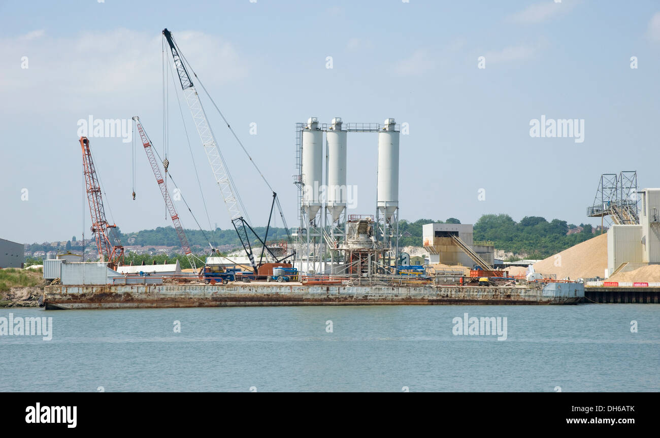 An industrial gravel plant. Storage of sand and gravel, with conveyor belts in an industrial setting by a dockside. Stock Photo