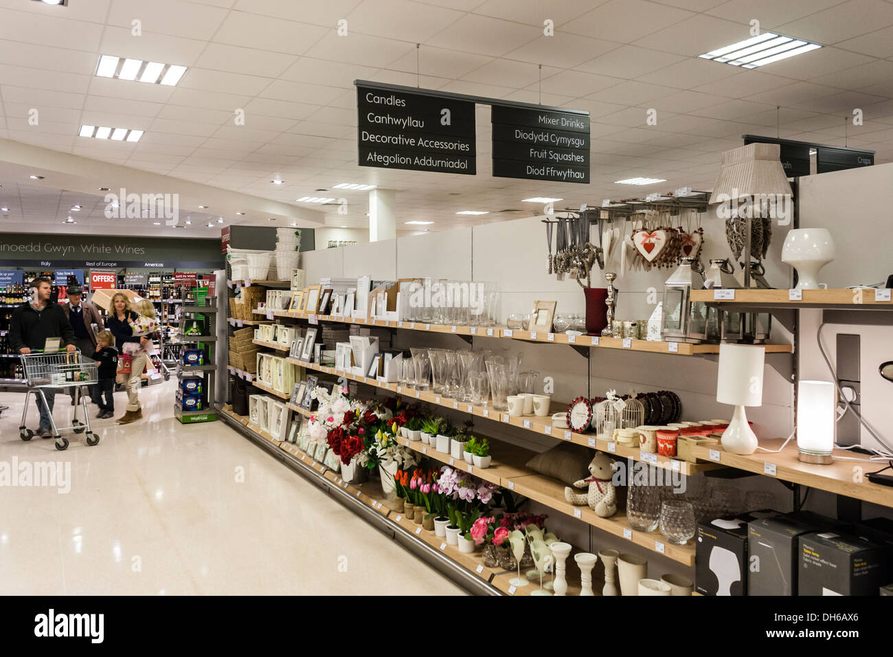 Young family browse the home products section in the aisles of a Waitrose supermarket in Wales with signs in Welsh and English. Stock Photo