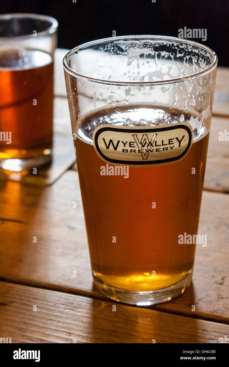 Pint of beer in a straight glass with a Wye Valley Brewery logo on a pub table. Talybont-on-Usk, Brecon, Powys, Wales, GB, UK Stock Photo