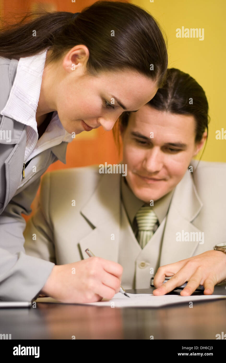 Woman signs a document in front of a men Stock Photo - Alamy