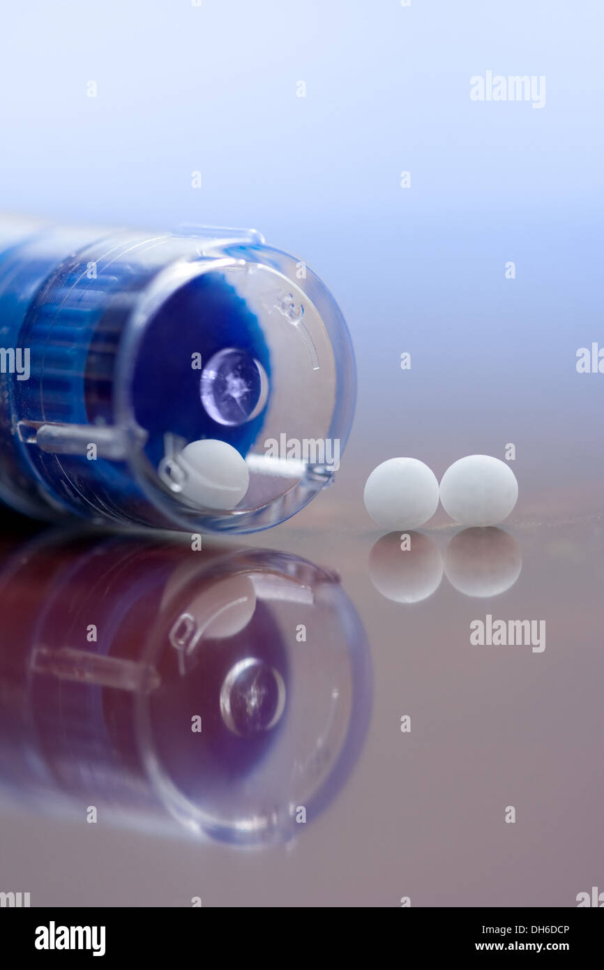 Extreme macro of homeopathic medications - container and small white balls Stock Photo