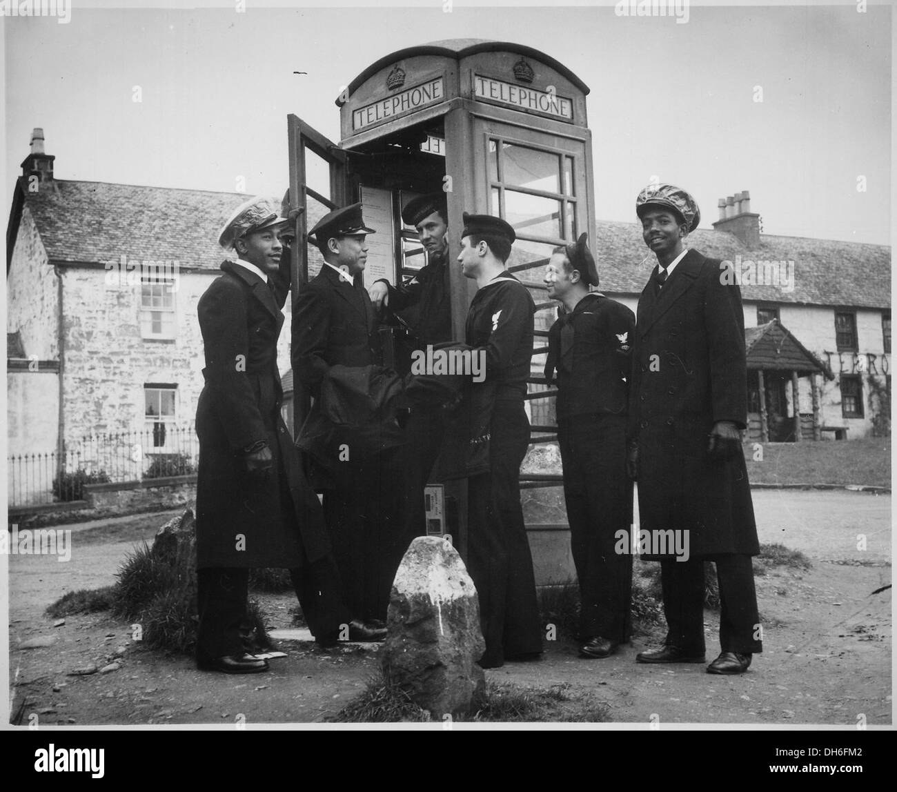 U.S. Coast Guardsmen make use of a telephone booth in Scotland. They are on liberty from their ship, a Coast Guard 513167 Stock Photo