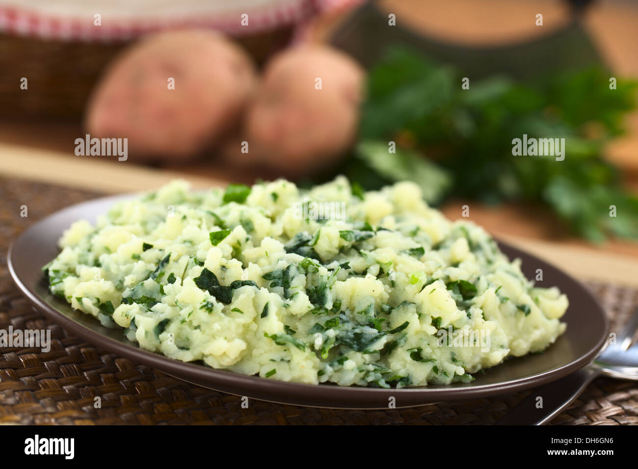 Mashed potatoes with fresh herbs on brown plate (Selective Focus, Focus one third into the mashed potato) Stock Photo