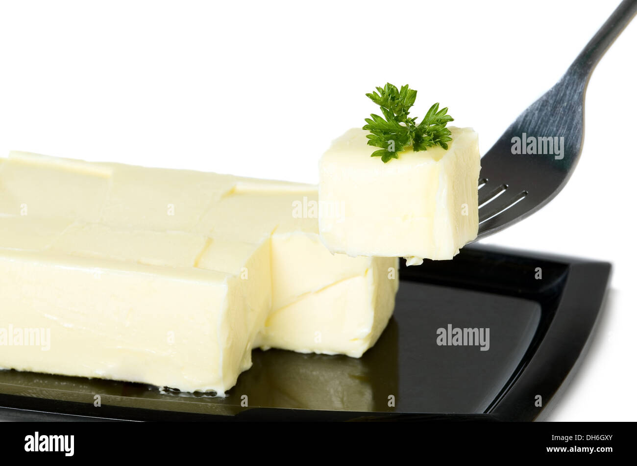 Yellow butter with parsley is being hold with fork, food concept Stock Photo