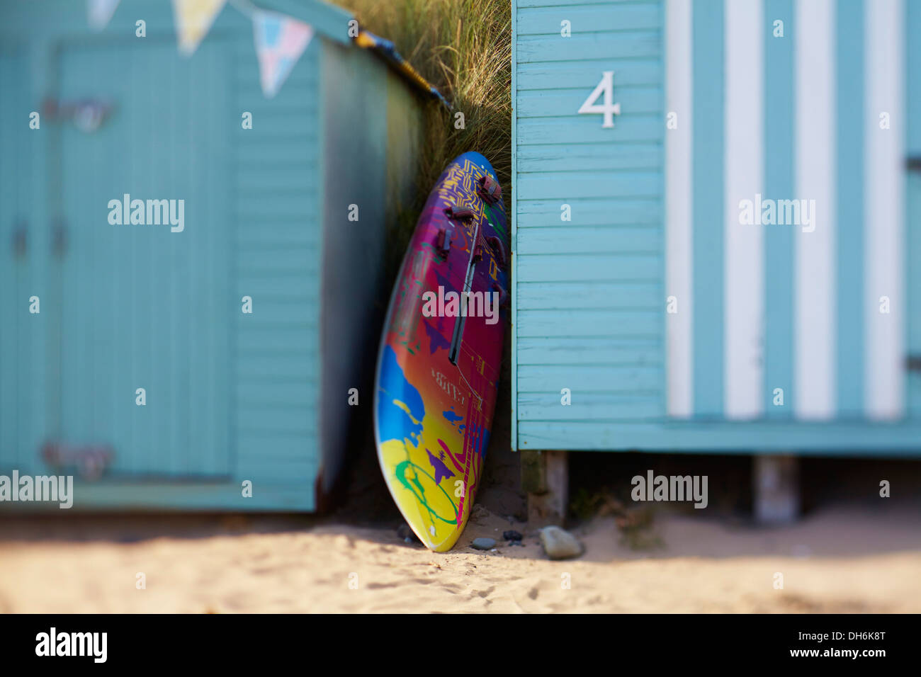 Surf board next to beach huts Stock Photo