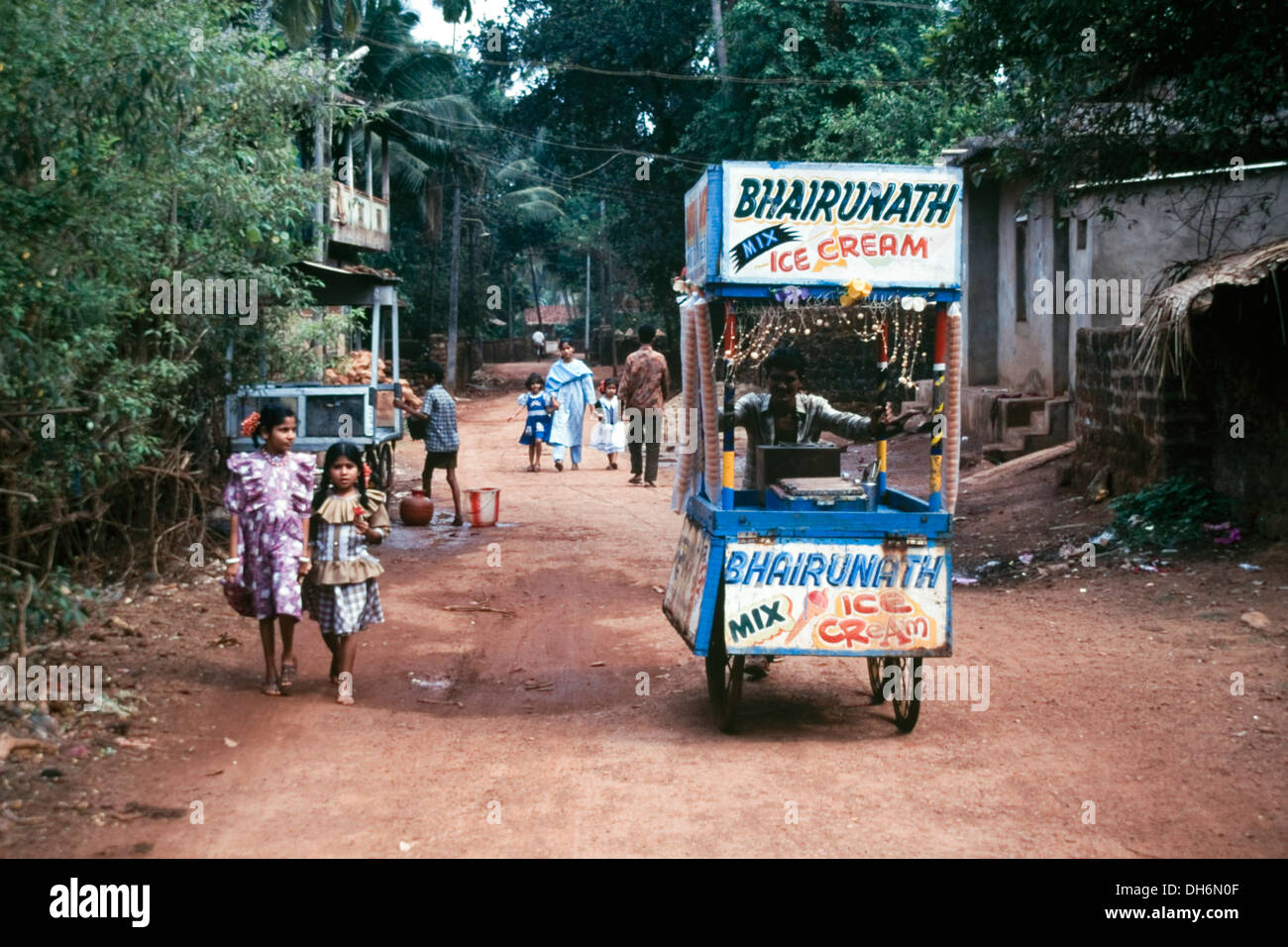 ice cream vendor pushing his old cart down a rural mud track street in goa india Stock Photo