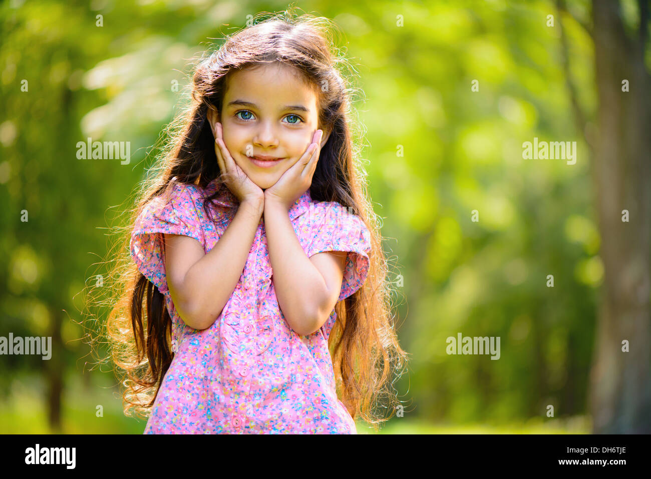 Portrait of hispanic girl with deep blue eyes in sunny park Stock Photo