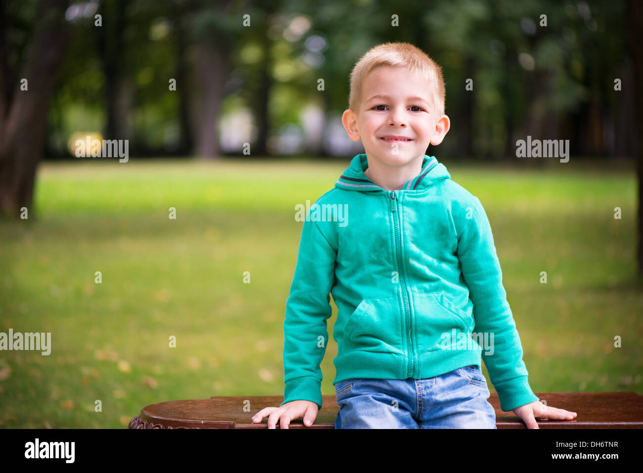 Cute little boy sitting on bench at park Stock Photo - Alamy