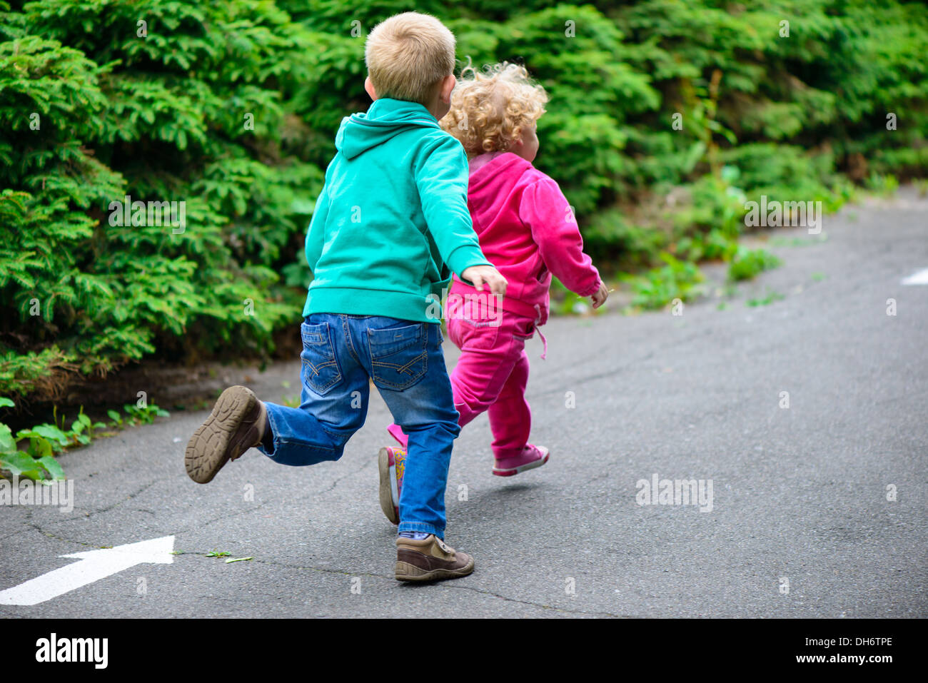 Little brother and sister running on footpath Stock Photo - Alamy