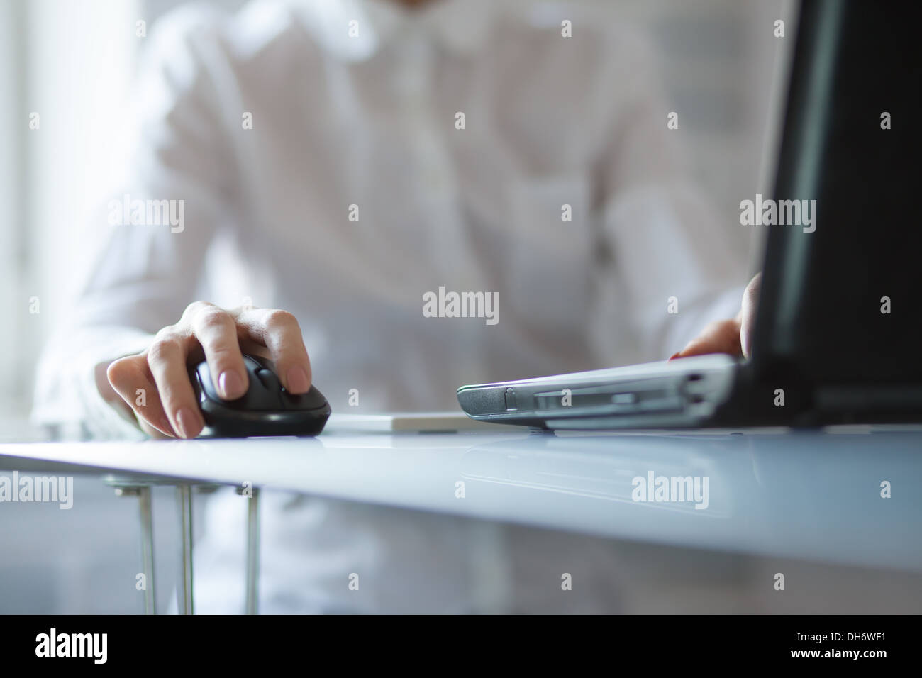 Woman's hand using cordless mouse on glass table Stock Photo