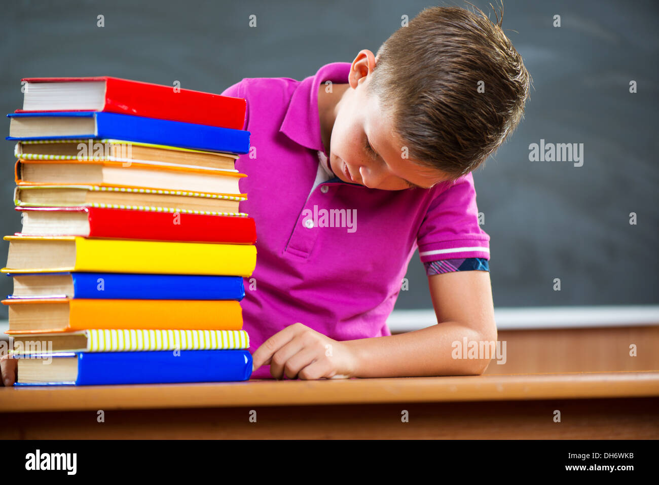 Adorable schoolboy with stack of books in classroom Stock Photo - Alamy