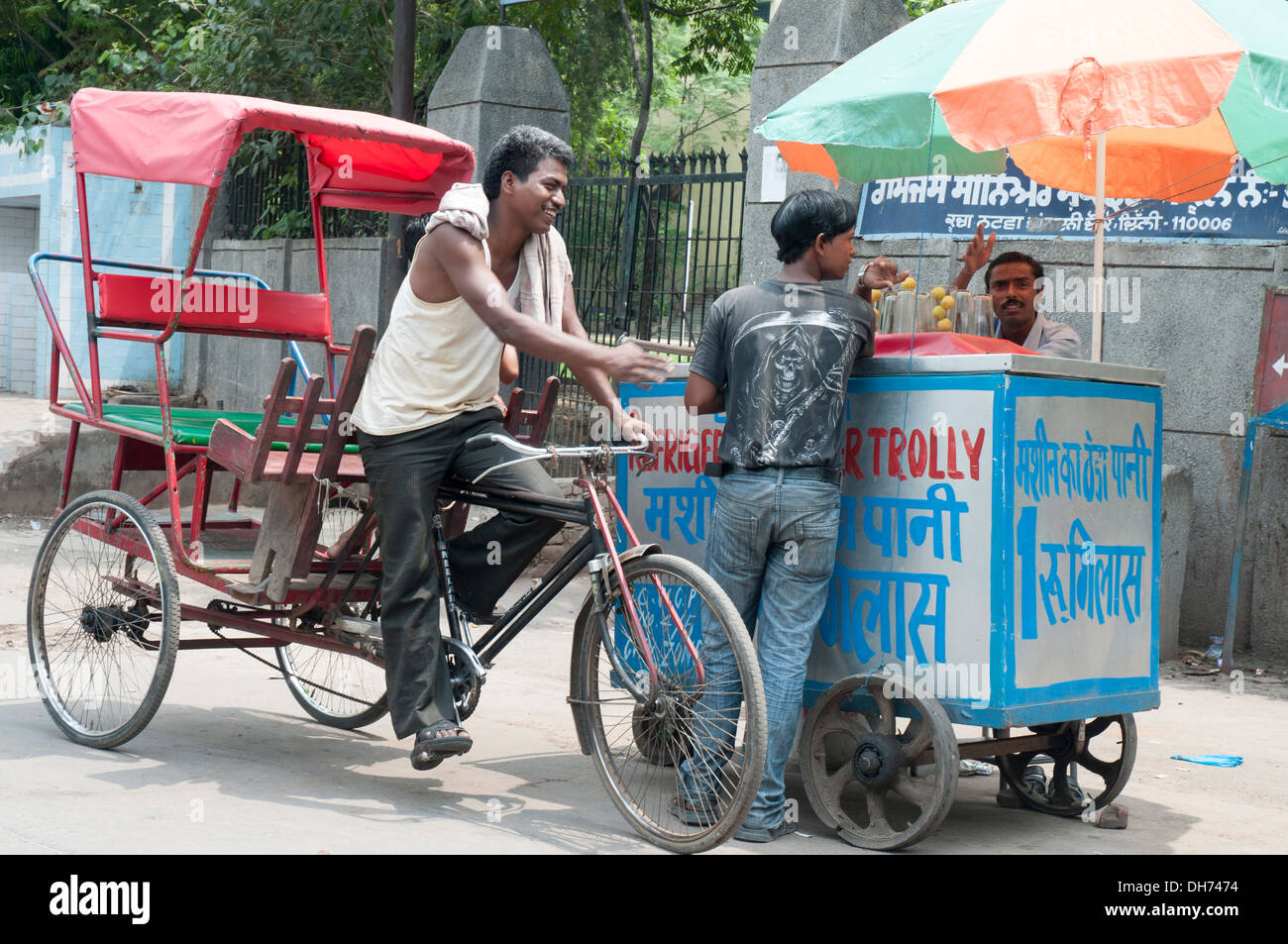 Cycle rickshaw rider chatting with an ice-cream vendor in Delhi, India Stock Photo