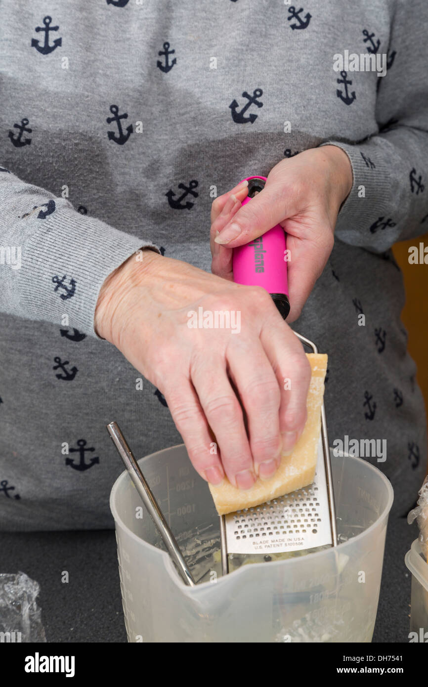 A housewife grating parmesan cheese. Stock Photo