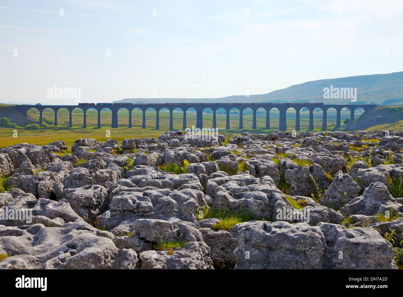 Steam train crossing Ribblehead Viaduct with limestone pavement in forground. Yorkshire Dales National Park North Yorkshire UK Stock Photo