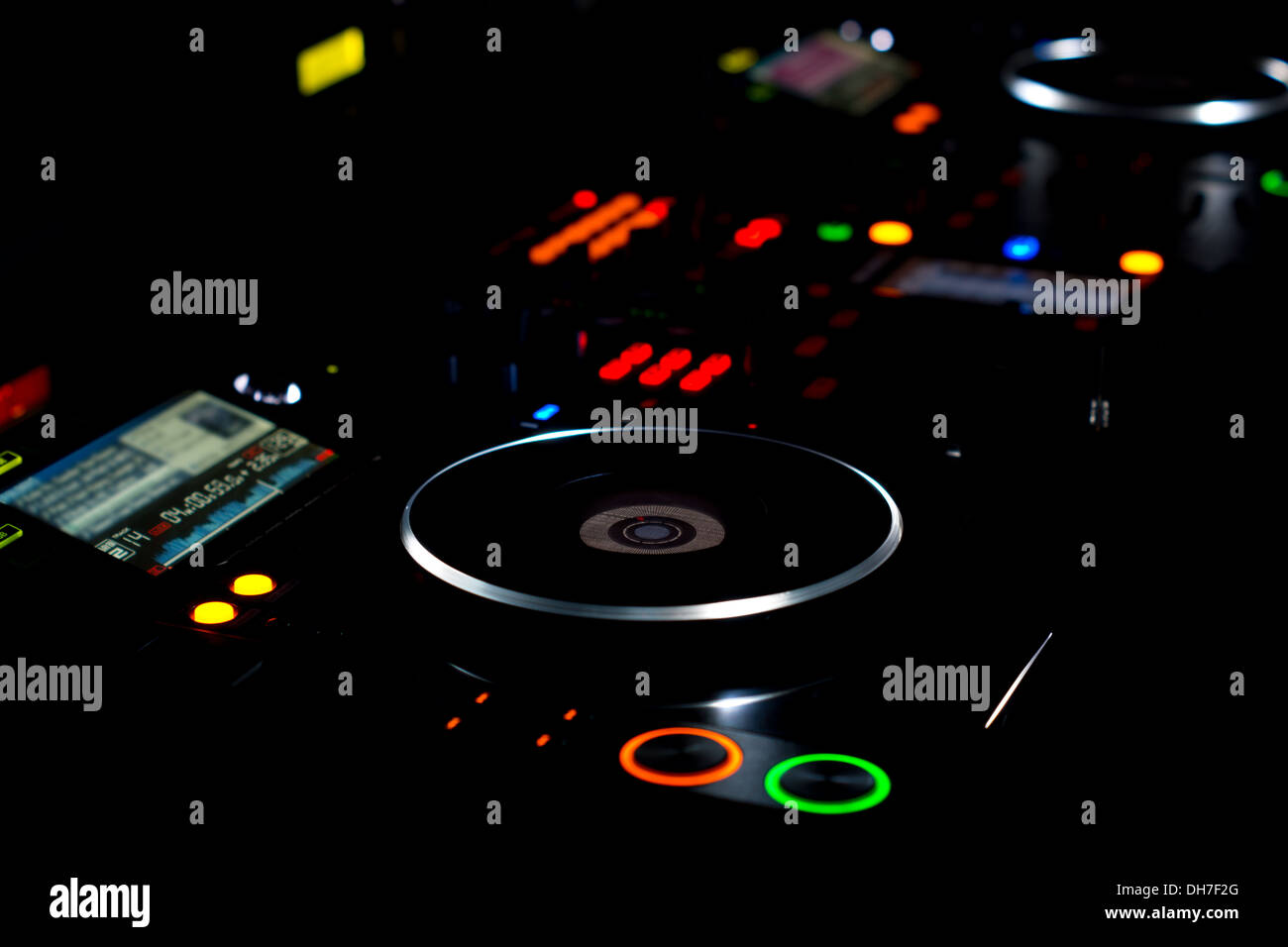 DJ turntable and music deck illuminated at night with colourful lights