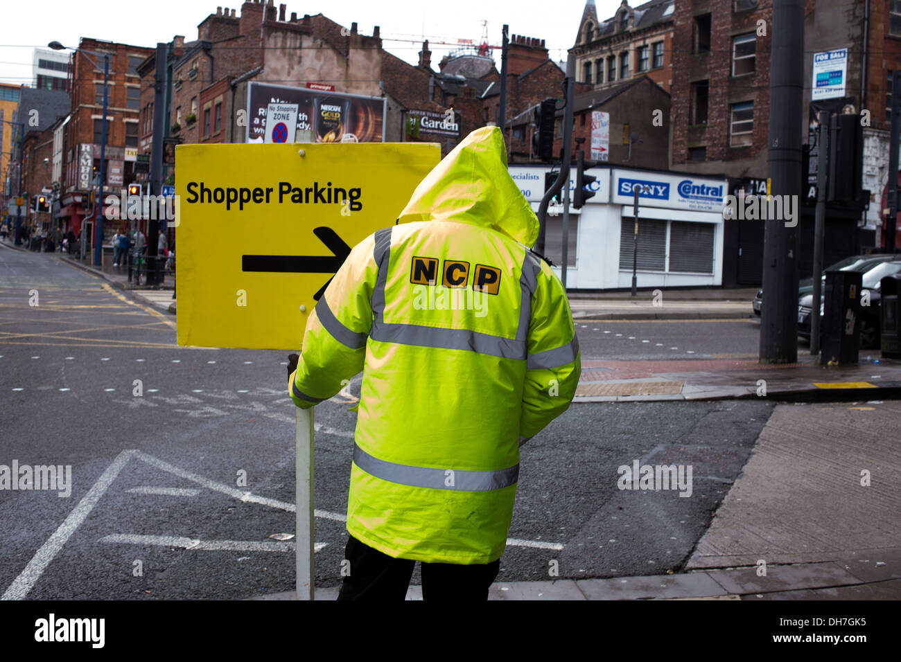 An NCP parking attendent directs drivers to shopper parking in a multi storey car park in Manchester City Centre Stock Photo