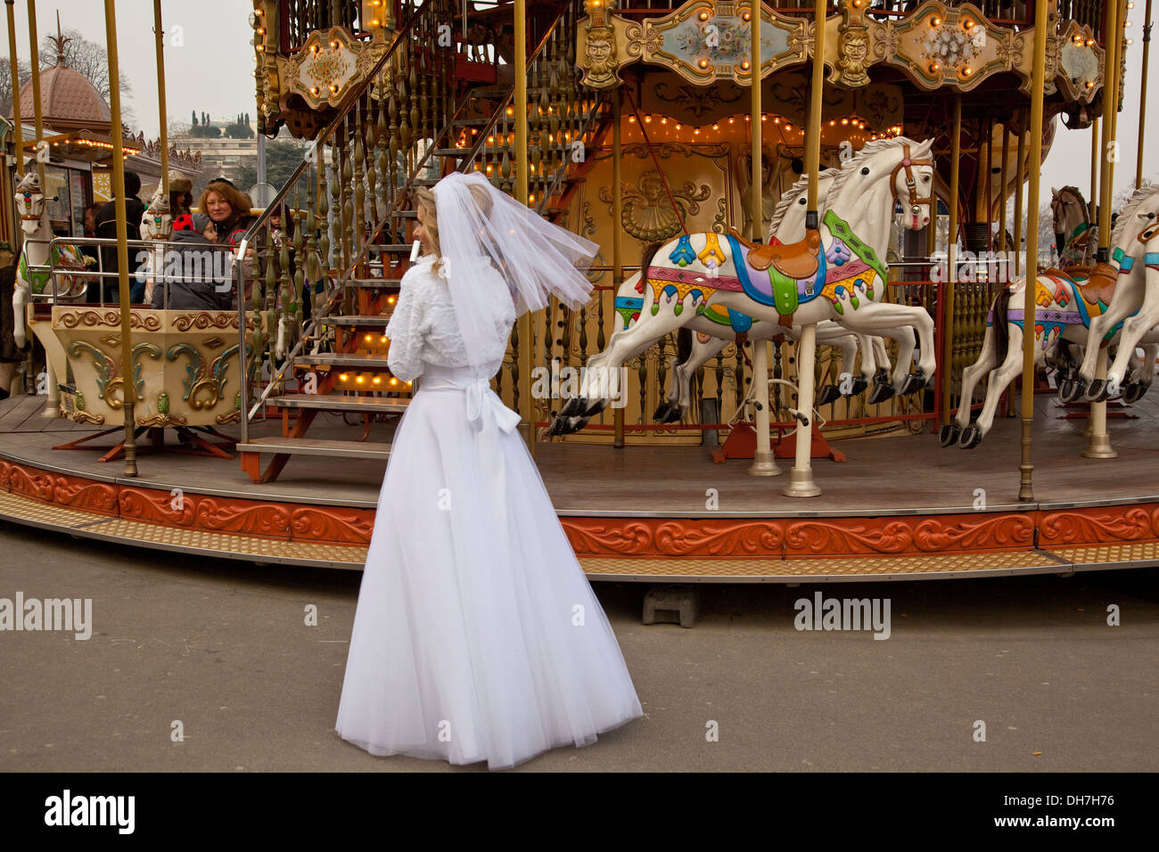 bride in wedding dress standing by a carousel in Paris Stock Photo