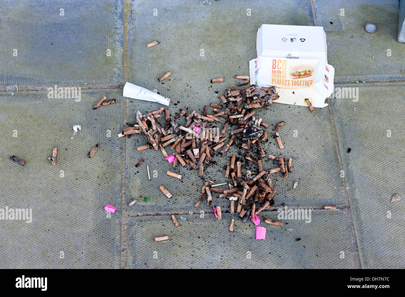 Dirty ashtray rubbish cigarette ends dropped on floor Stock Photo