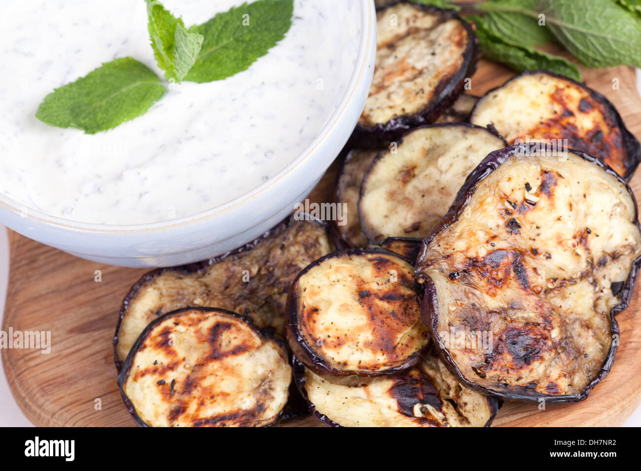 grilled aubergine with mint sauce on chopping board. Stock Photo