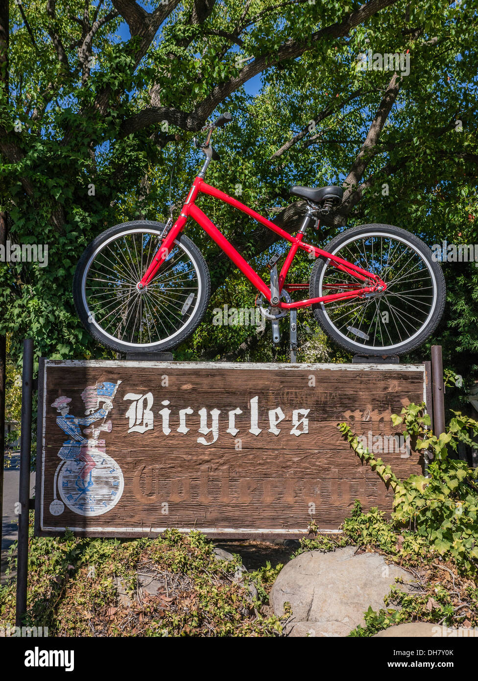 Red bike atop weathered wooden bicycle shop sign in Ojai, California