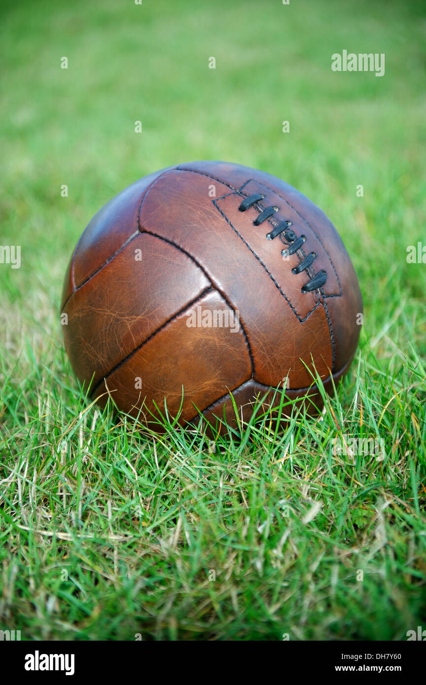 Vintage brown football soccer ball sits in green grass field Stock Photo