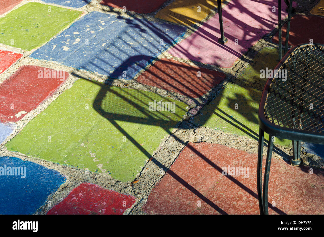 Chair casting a shadow onto the colorful painted cement floor of the Spanish Village Art Center. Balboa Park, San Diego. Stock Photo