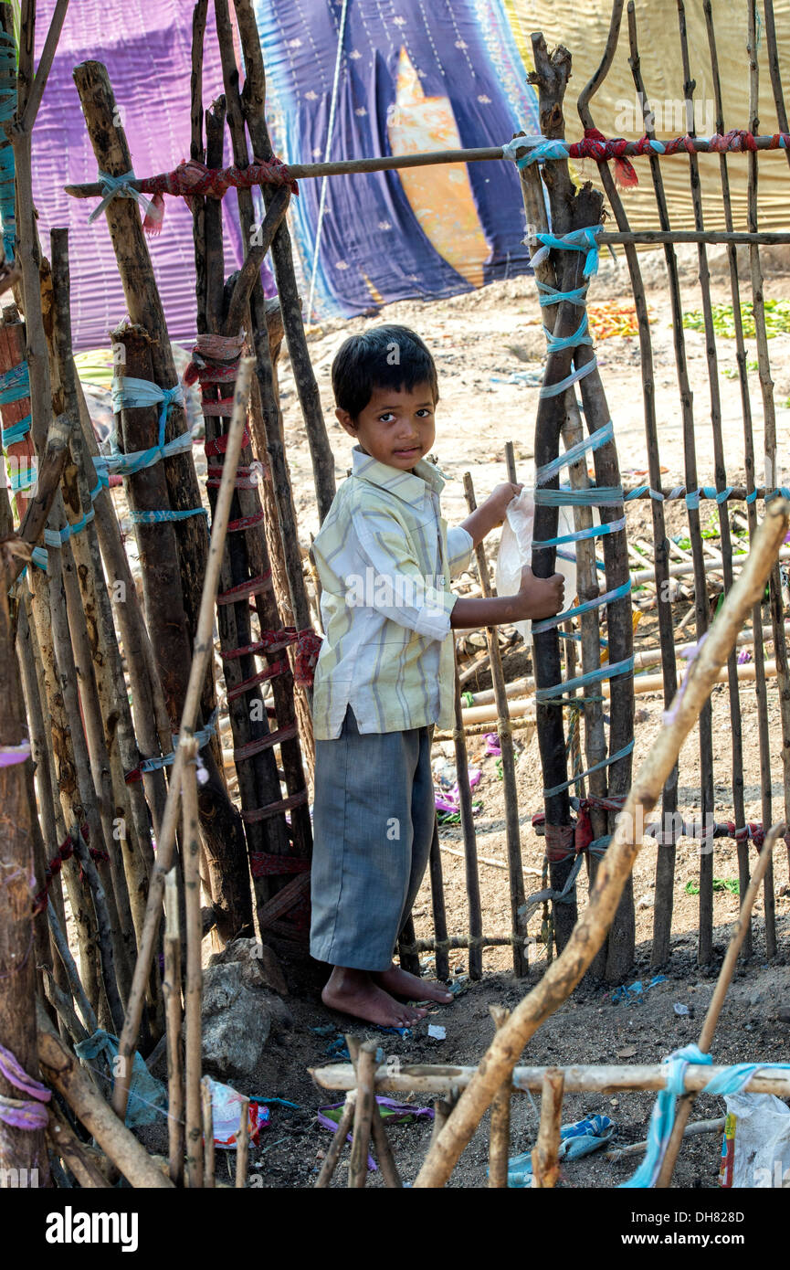 Indian lower caste boy standing inside a goat pen in front of his  bender / tent / shelter.  Andhra Pradesh, India Stock Photo