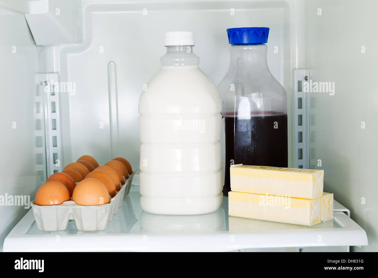 Horizontal photo of milk, eggs, butter and juice on glass shelf inside