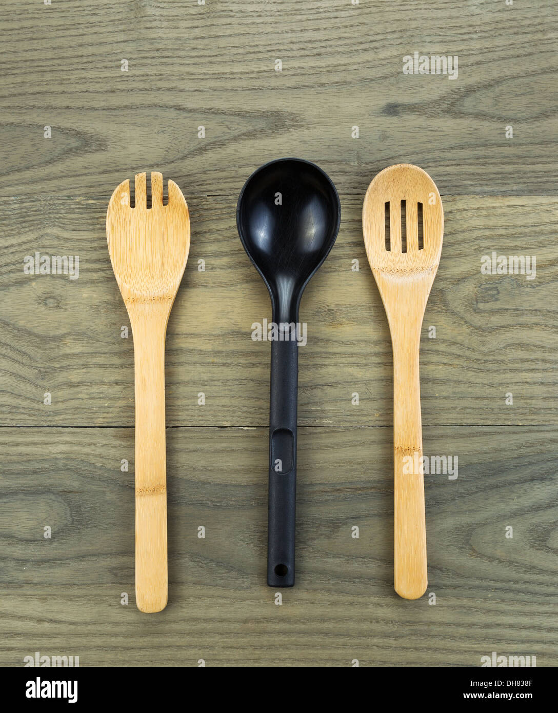 Photo of three kitchen spoons, two of them wooden, on aged white oak boards Stock Photo
