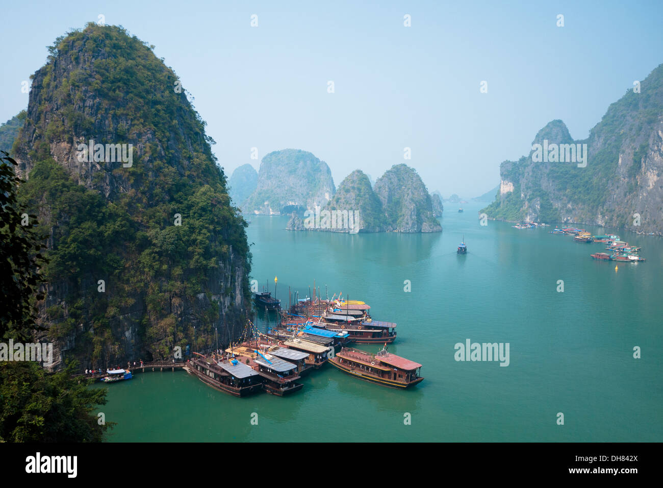 A view of the spectacular limestone karst formations rising above boats moored  in Halong Bay, Vietnam. Stock Photo