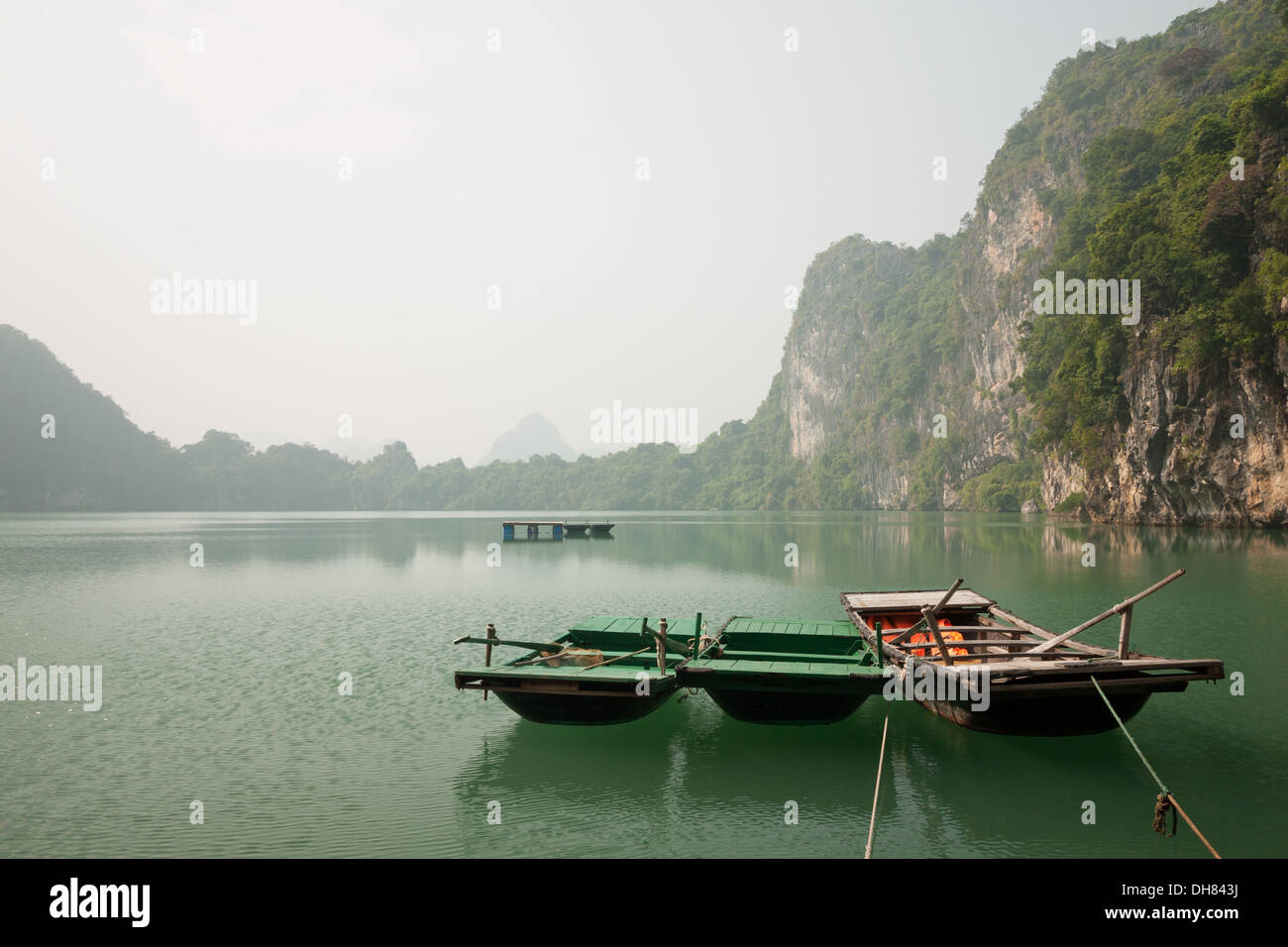 A view of rowboats and karst limestone rock formations characteristic of Lan Ha Bay in Halong Bay, Vietnam. Stock Photo