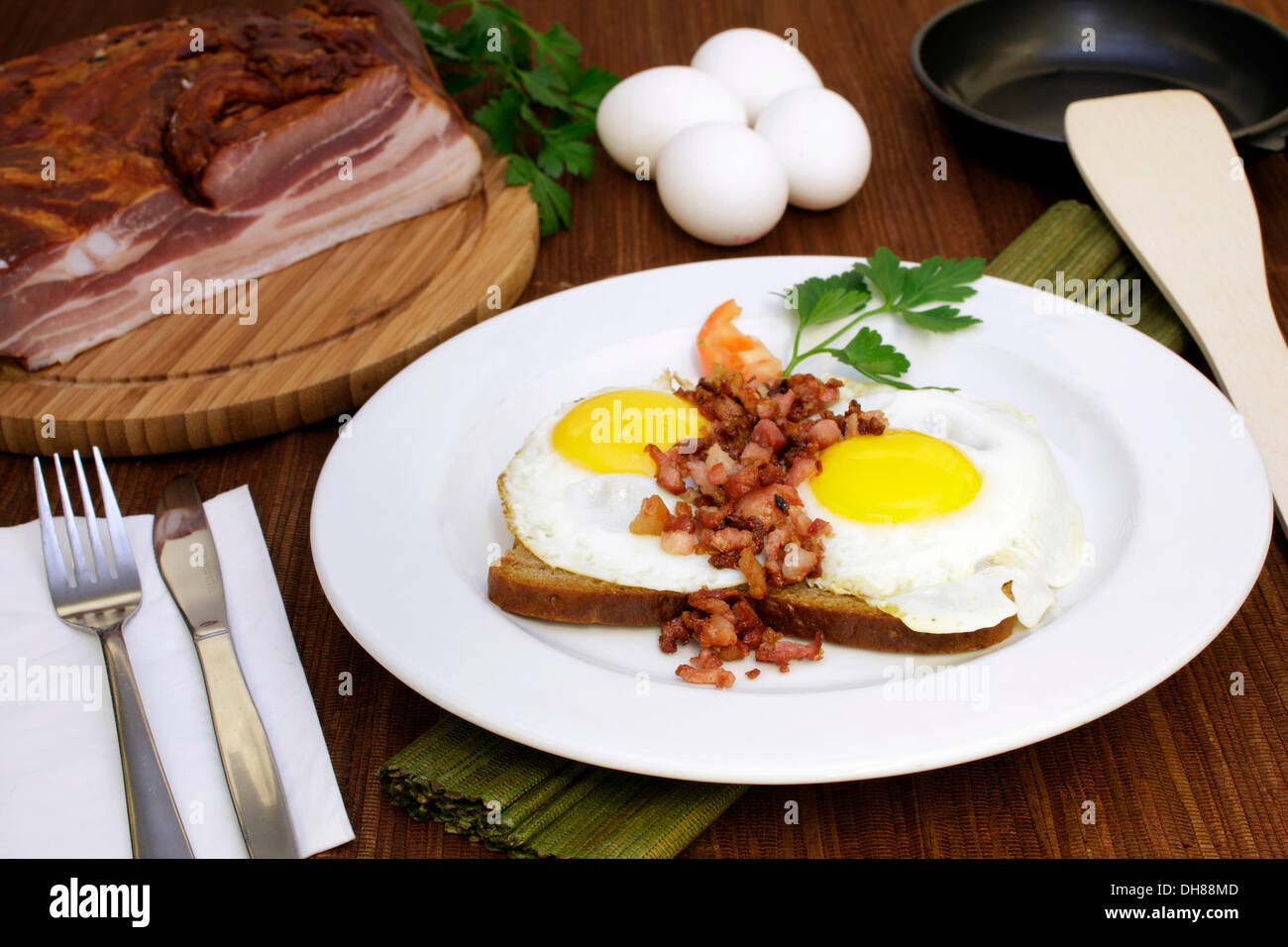 Fried eggs with fried bacon bits on bread, tomato slice, Italian