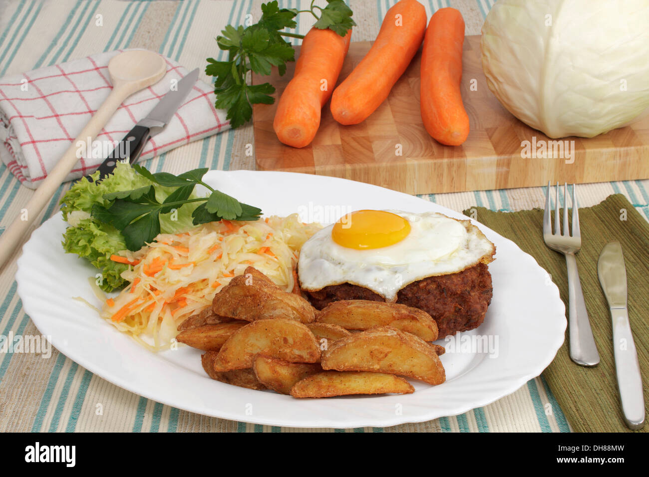 Farmers meat ball, hamburger steak, fried egg, baked potatoe wedges, coleslaw, carrots, white cabbage and flat leaf parsley on Stock Photo